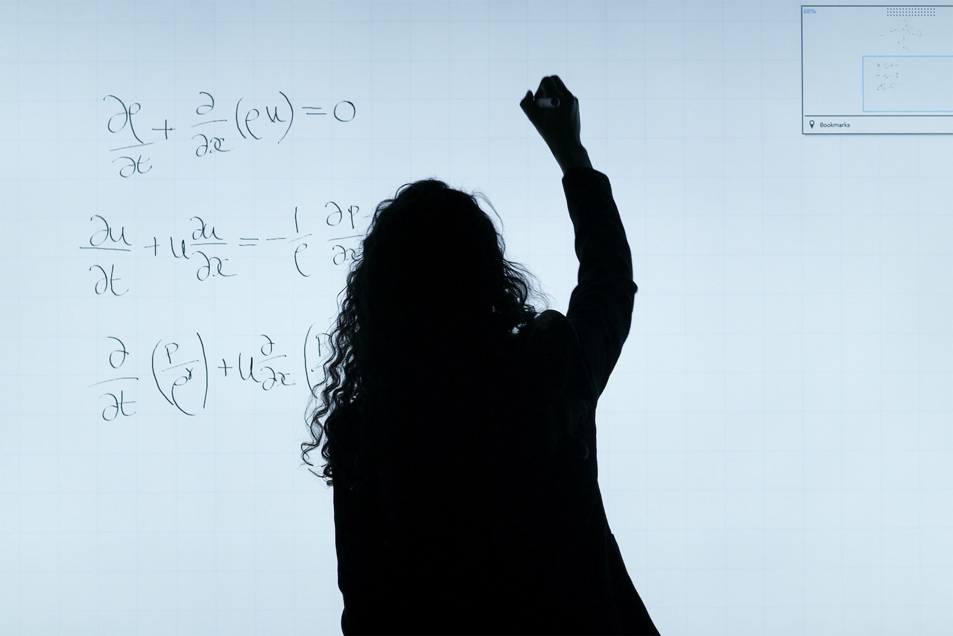 Silhouette of a person writing out a calculation on a white board